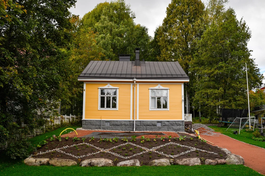 A house behind a mown lawn and planted beds