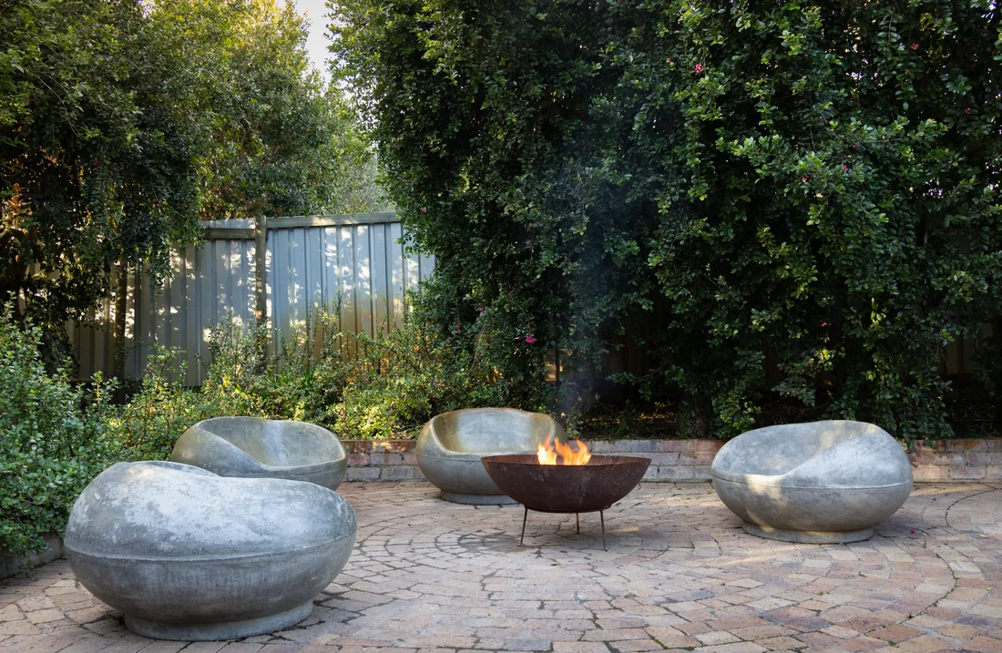 A fire pit with stone seating in a planted garden